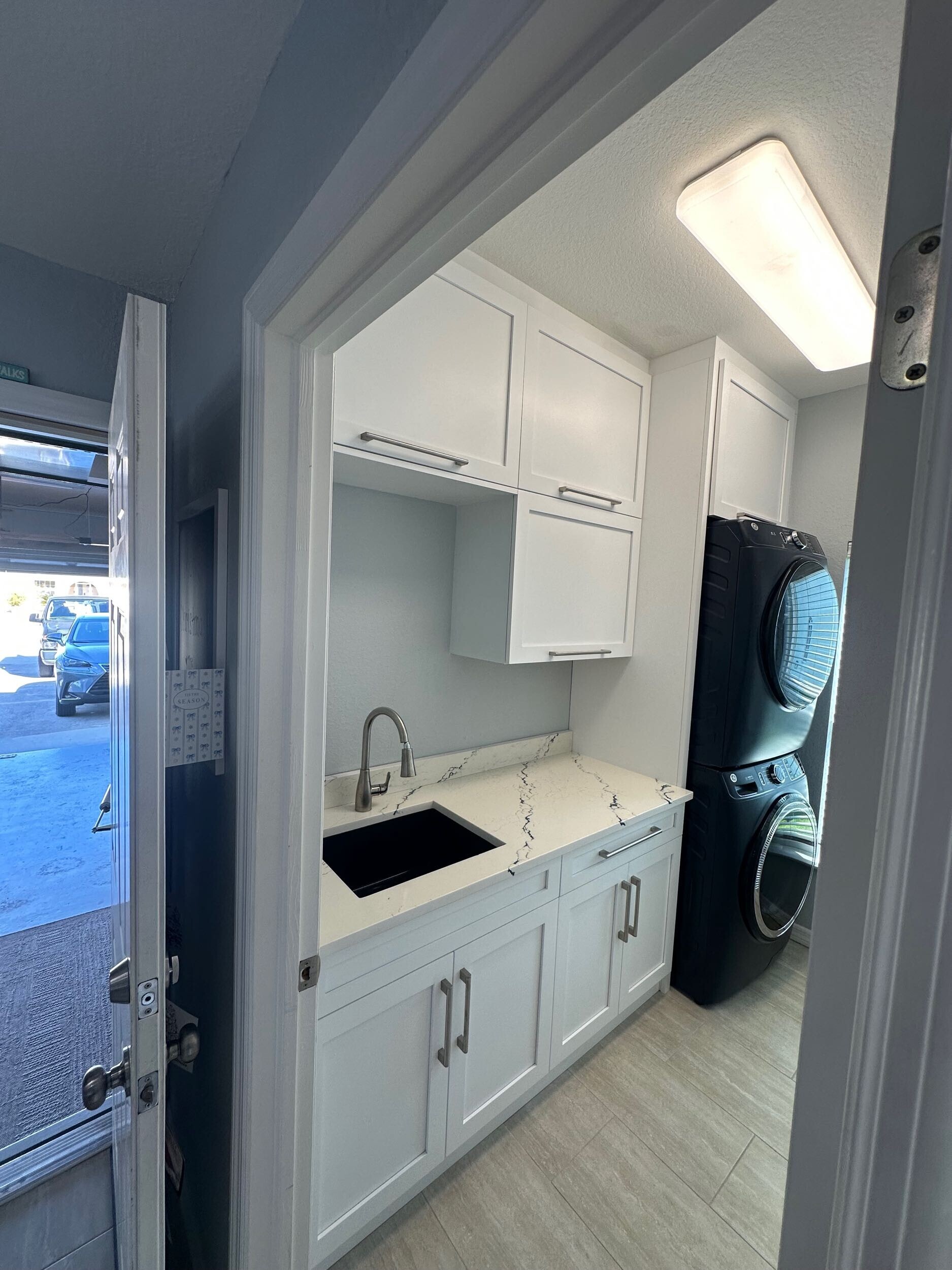 Completed laundry-room renovation with appliances, sink and organized storage by Proskillz Remodeling