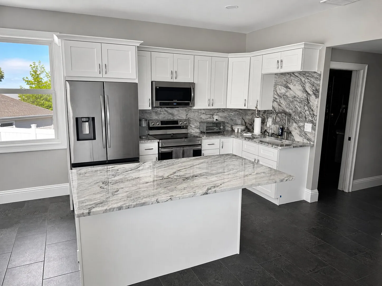 Completed Proskillz kitchen with a pale peninsula countertop and white cabinetry